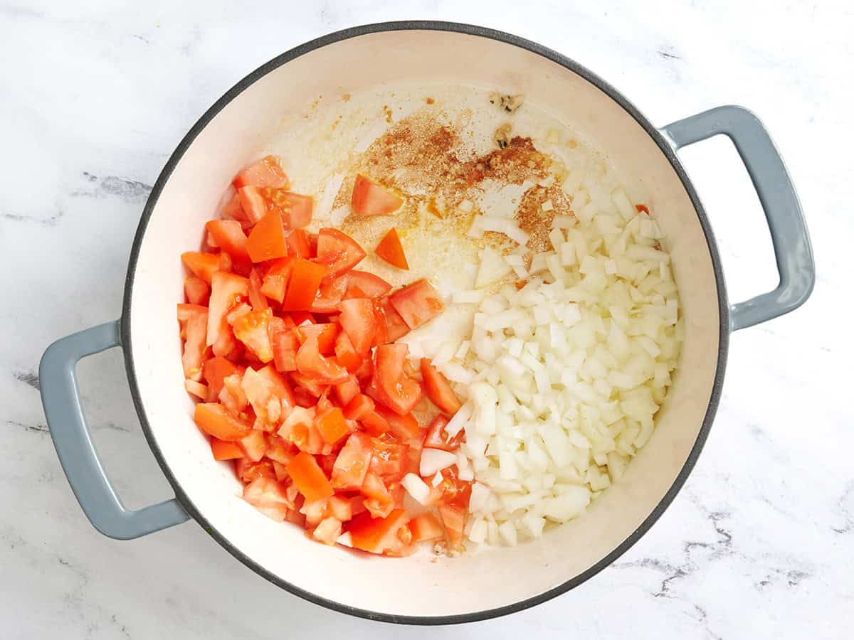 Diced onion and diced tomatoes in a pot.