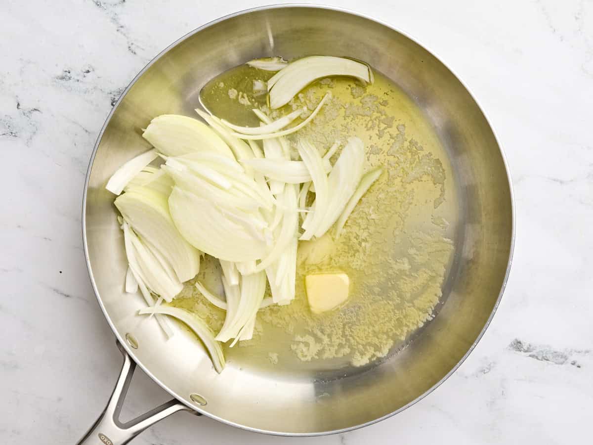 Sliced onions in a skillet with butter.