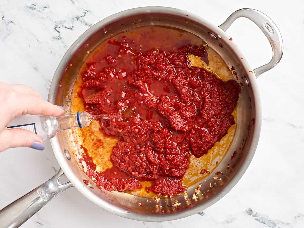 Vodka added to a skillet with tomato paste.
