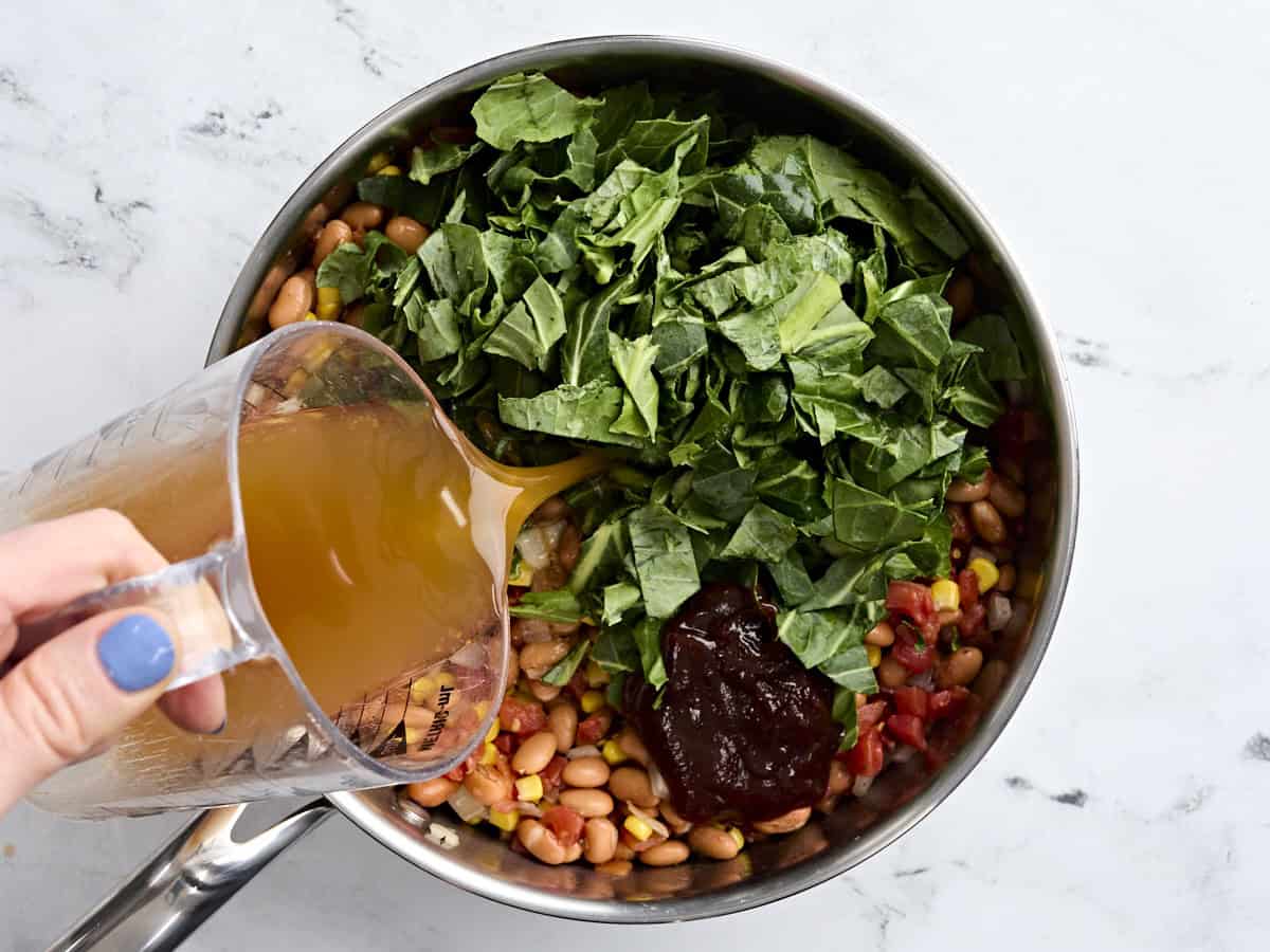 Southern greens, BBQ sauce, and broth added to a skillet to make BBQ greens and beans.
