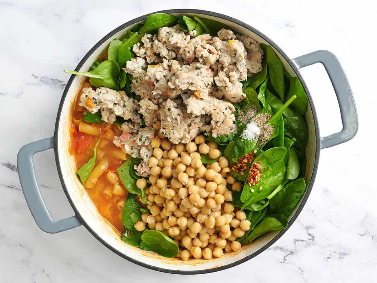 Browned ground chicken, chickpeas, and spinach added to sauteed veggies and vodka sauce in a pot.