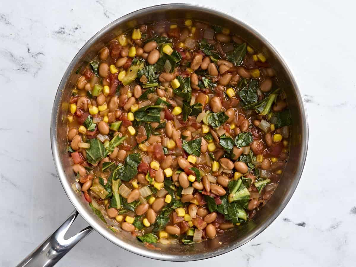Finished BBQ beans and greens in a skillet.