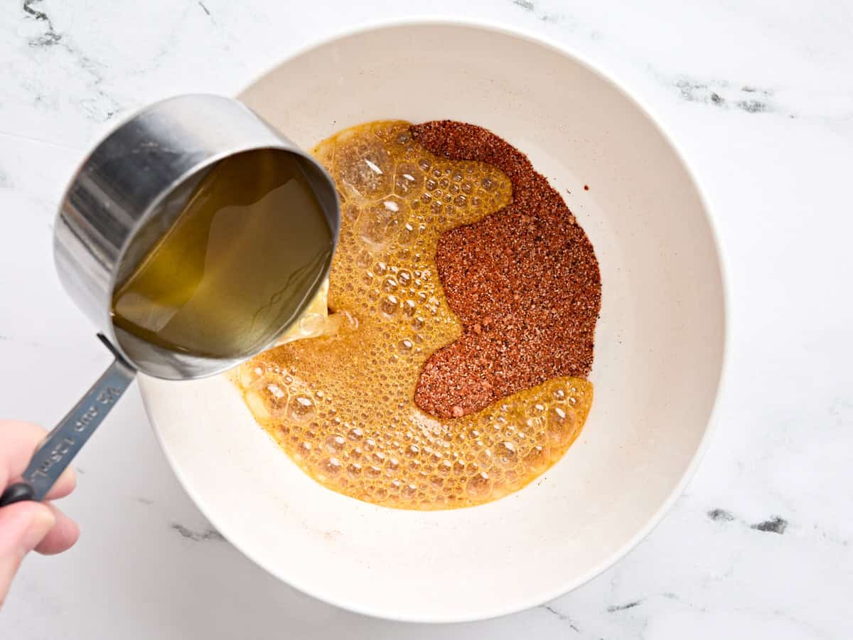 Hot oil being poured into a bowl of Nashville hot chicken seasoning.