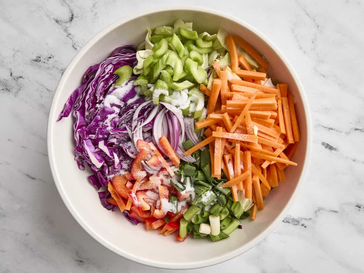 Prepped veggies in a mixing bowl with salt.