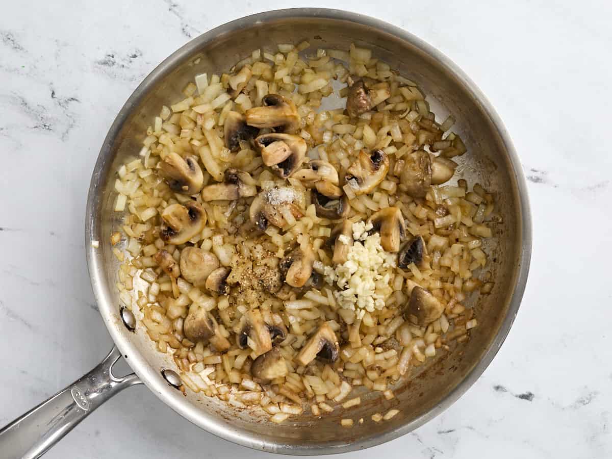 Sauteed onions and mushrooms in a skillet with minced garlic added.