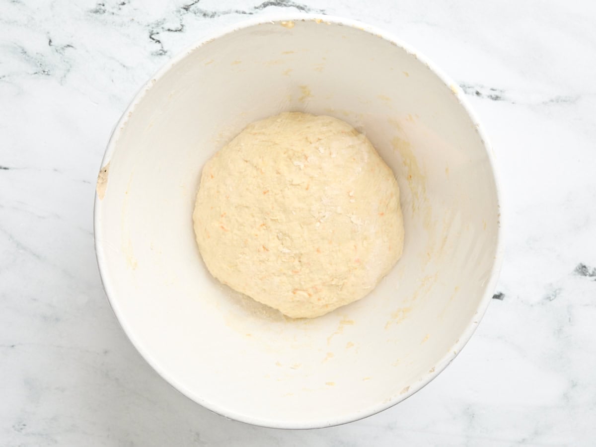 A ball of homemade orange dough in a mixing bowl.