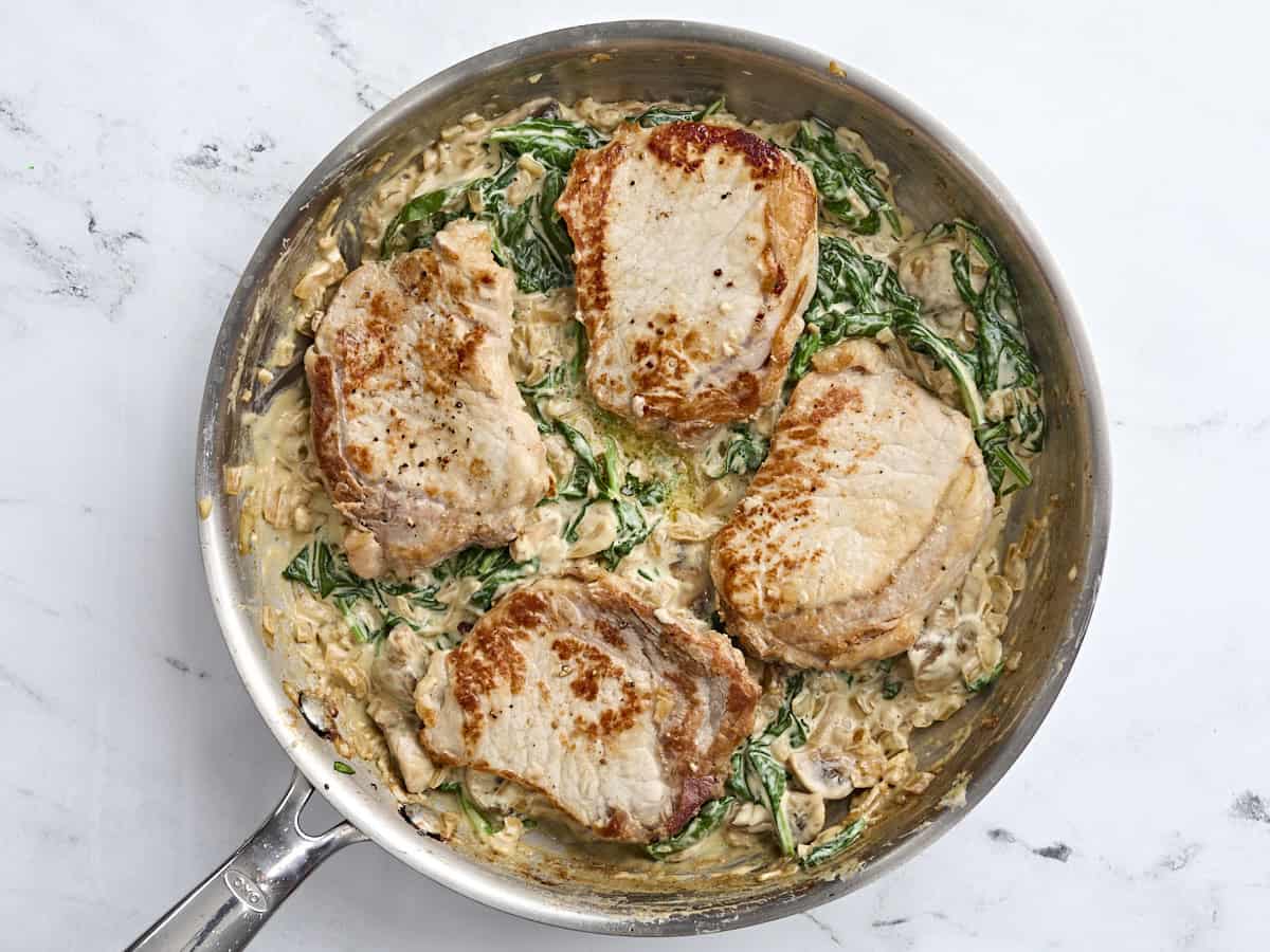 Finished creamy pork chops in a skillet.