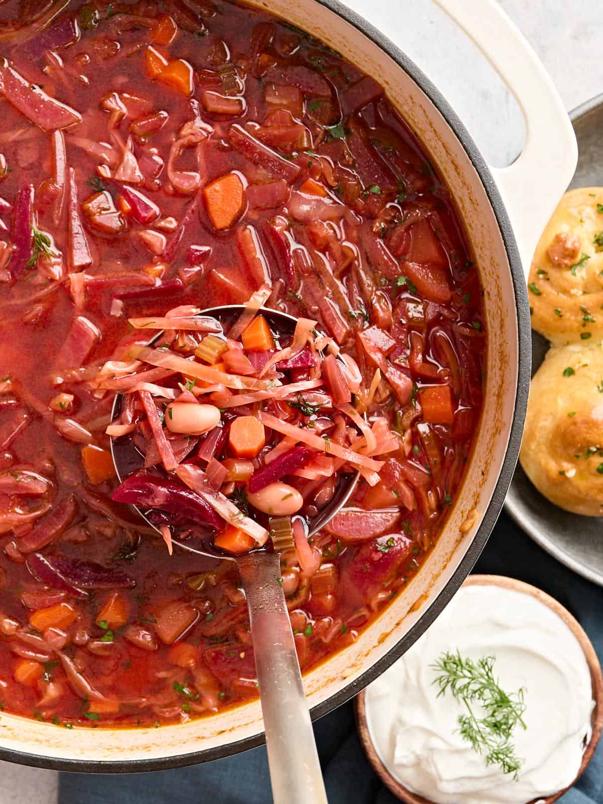 Overhead view of a pot of homemade borscht, with some in a soup ladle.