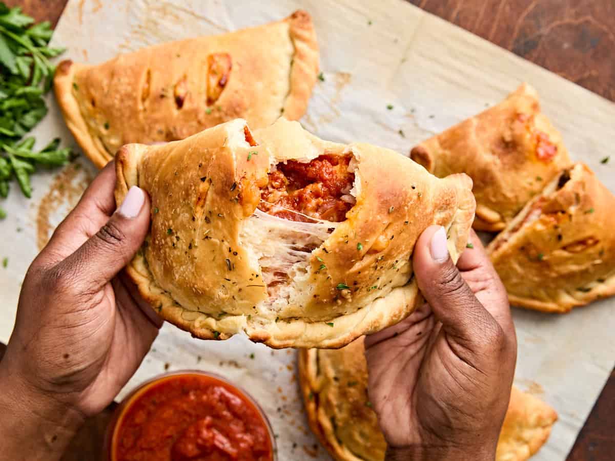 Hands breaking open a homemade pepperoni calzone.