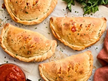 Overhead view of calzones on a piece of parchment paper.