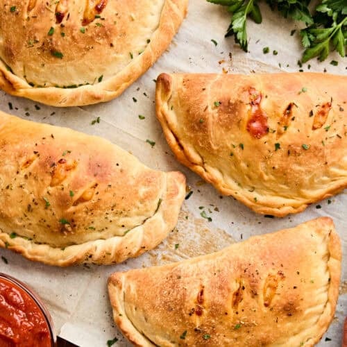 Overhead view of calzones on a piece of parchment paper.