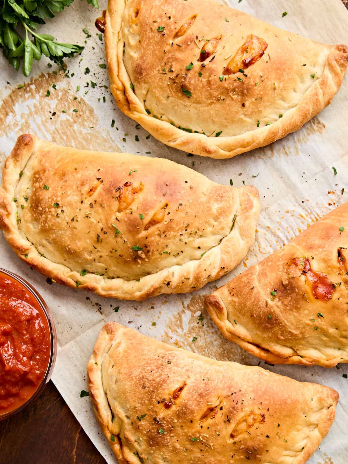 Overhead view of calzones on a piece of parchment paper.