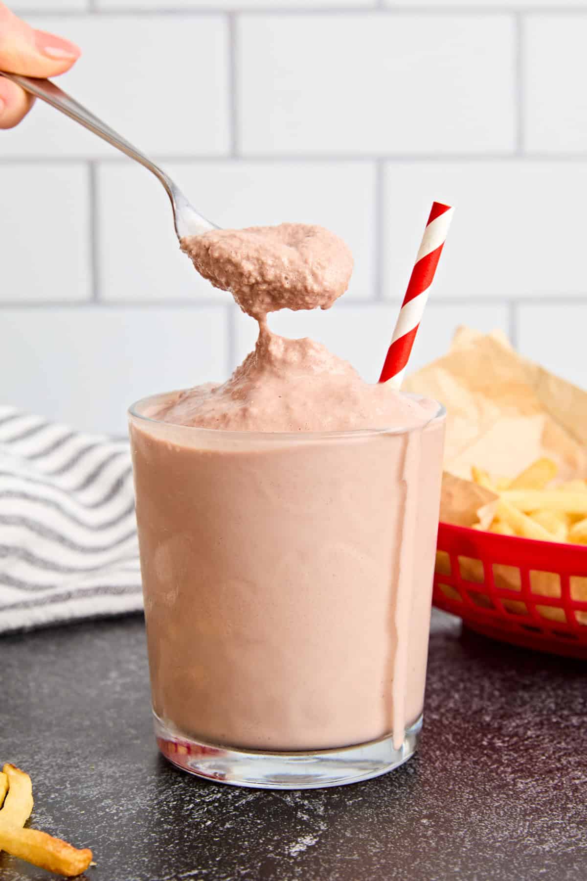 A spoon taking some chocolate frosty from a glass.