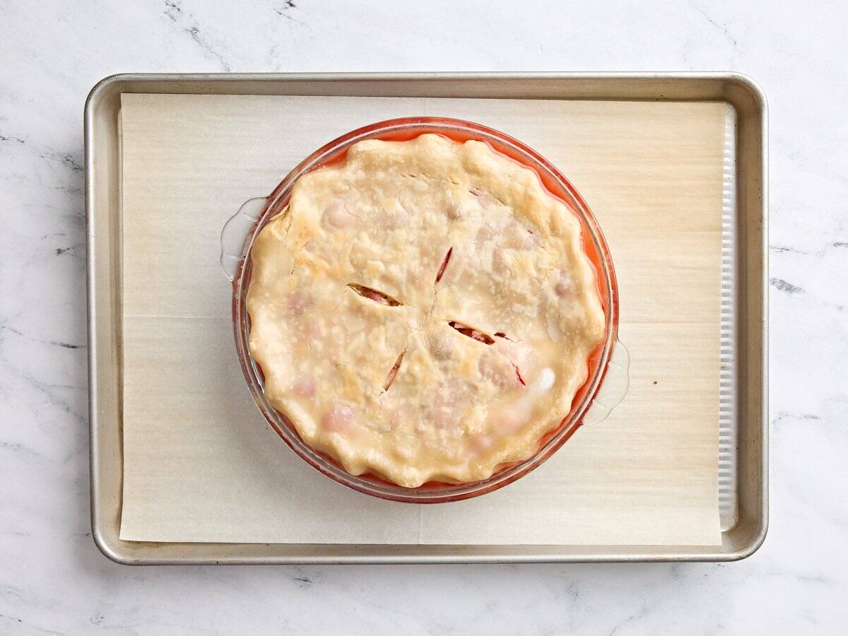 A homemade rhubarb and strawberry pie half way through baking.