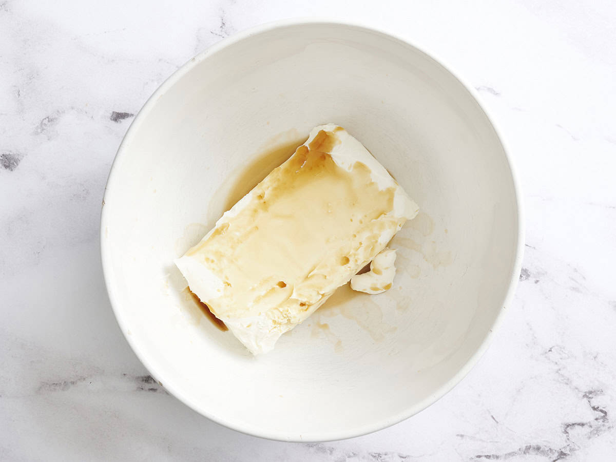 Vanilla extract and a block of cheese in a mixing bowl.