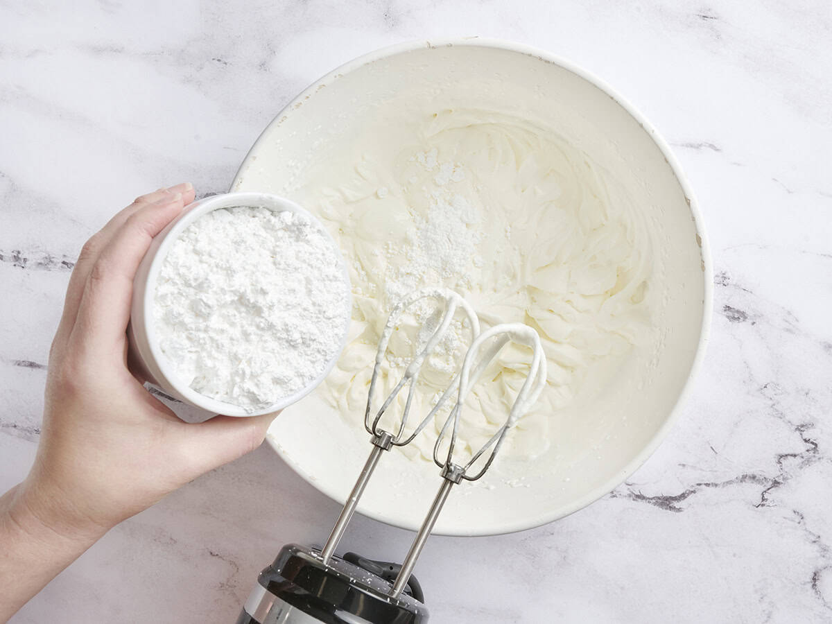 Powdered sugar being added to whipped cream.