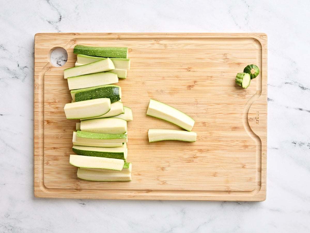 Zucchini spears on a cutting board.