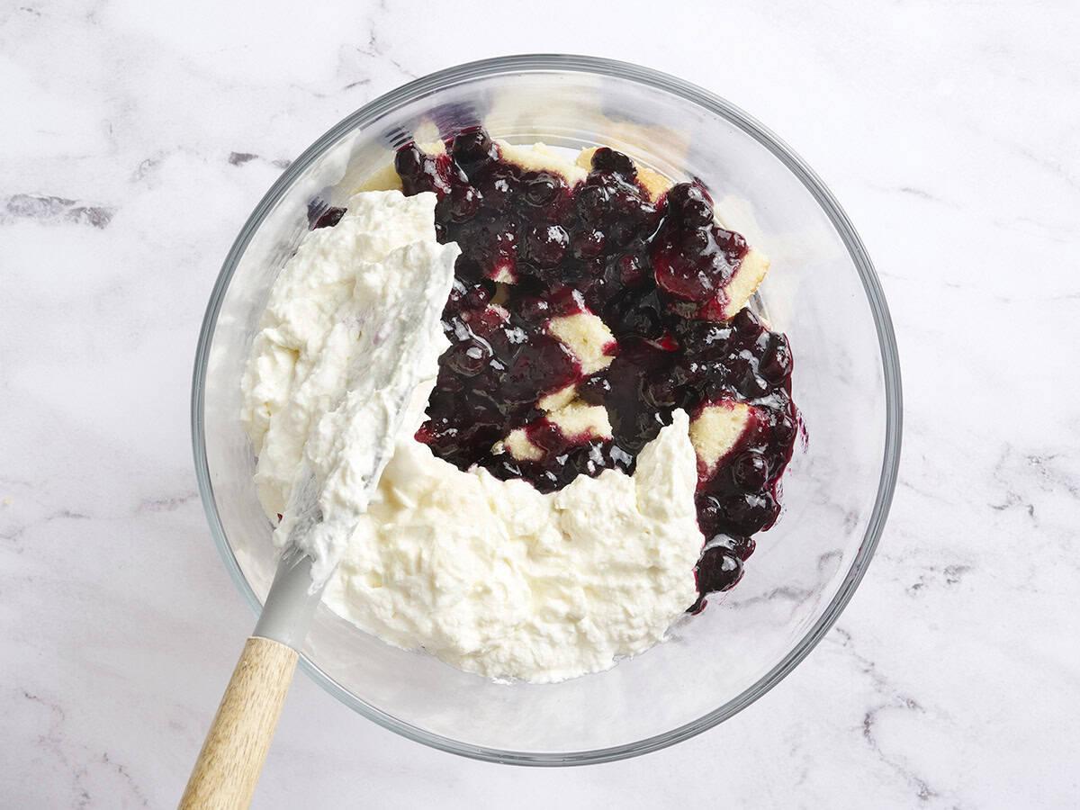 Cream cheese filling layer being added to a trifle dish.
