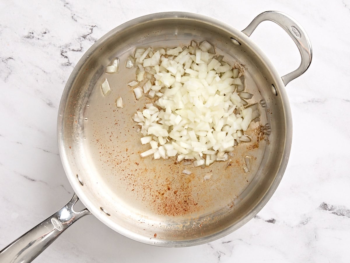 Diced onions sauteeing in a skillet.