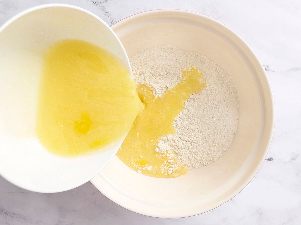 The wet ingredients being poured into the dry ingredients to make blueberry rhubarb muffins.
