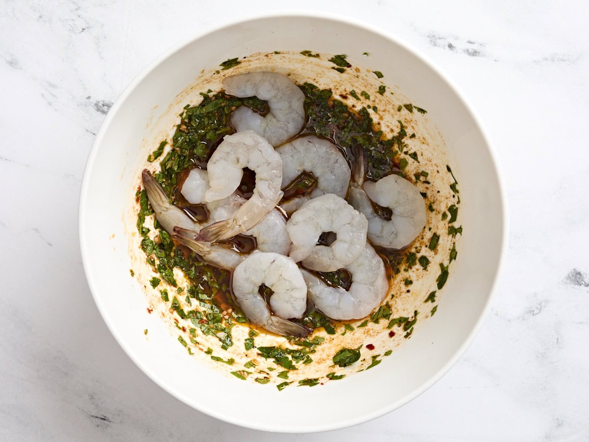 Raw shrimp added to the bowl of marinade.