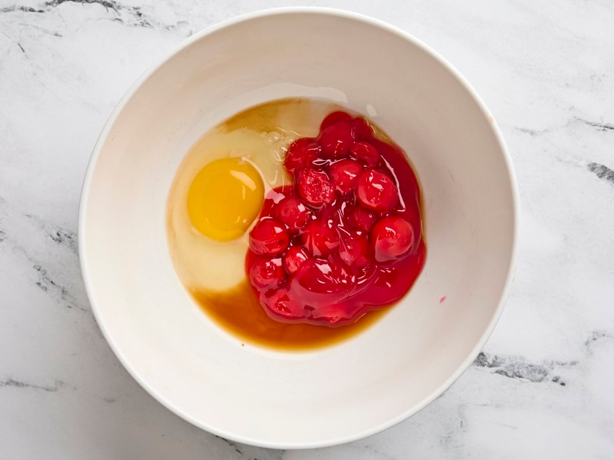 Cherry pie filling, egg, and vanilla extract in a bowl.