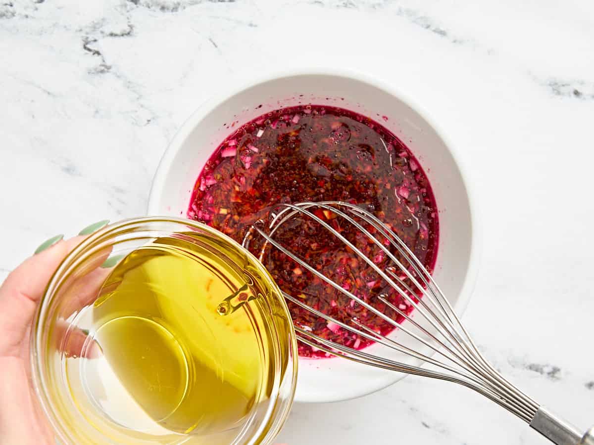 Olive oil being streamed into the dressing for a beet salad.