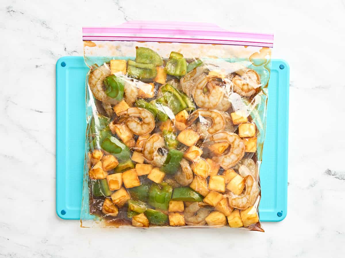Shrimp, pineapple, and bell pepper in a ziplock bag with a marinade.