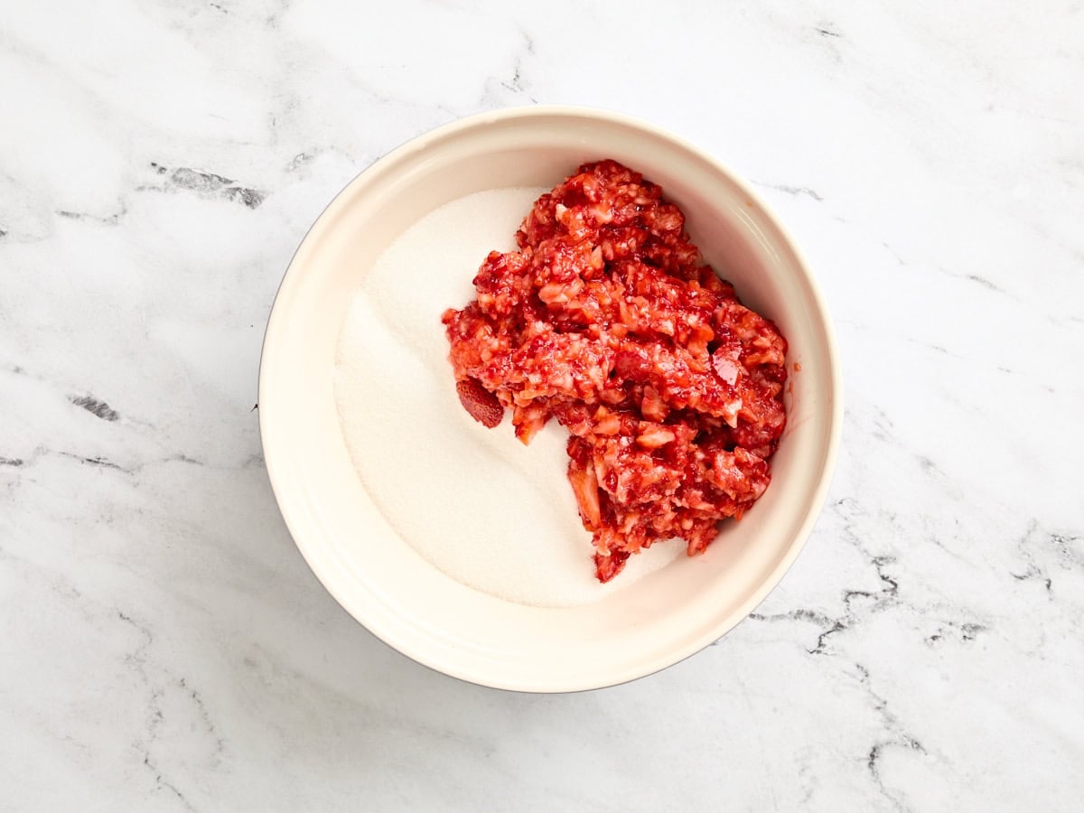 Coarsely chopped strawberries and granulated sugar in a bowl.