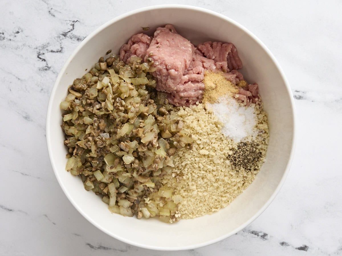 Cooked mushrooms and onions with panko bread crumbs and ground turkey in a bowl.