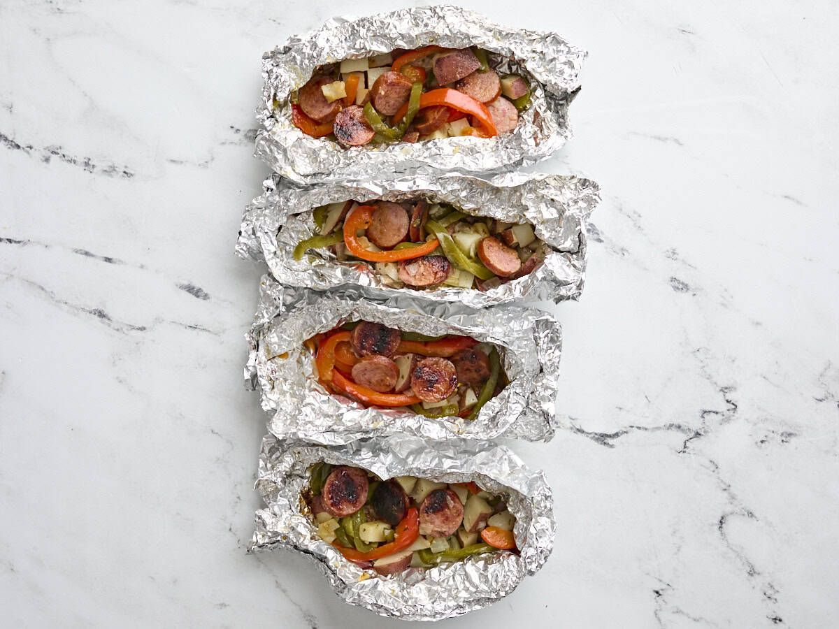 Finished grilled sausage and peppers foil packets.