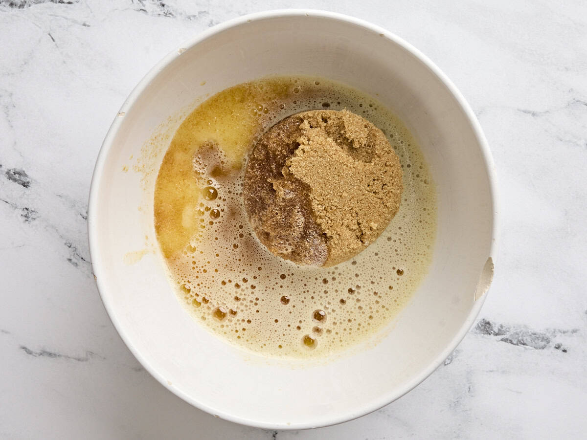 Brown and white sugar added to a bowl of browned butter.