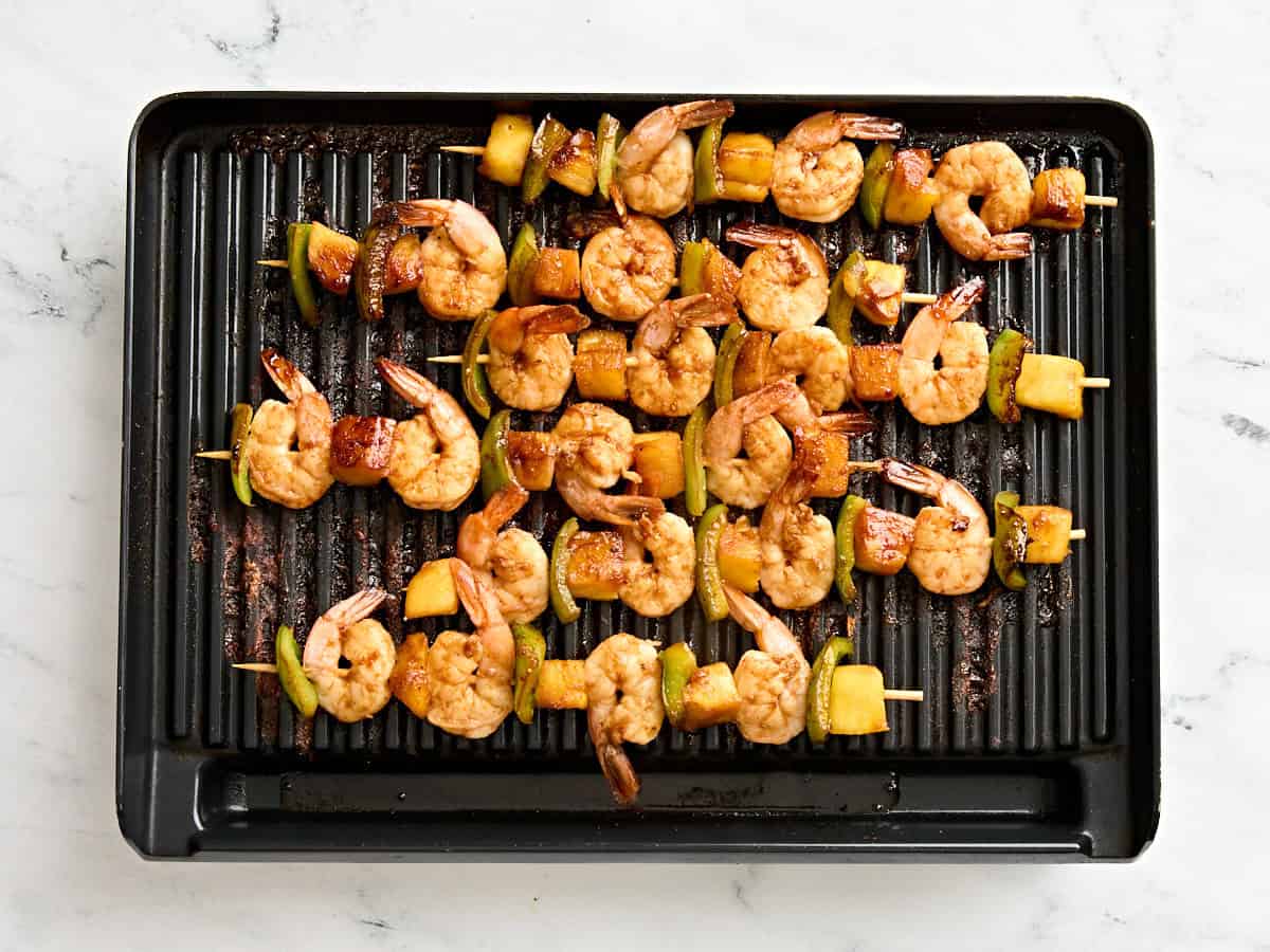 Grilled shrimp and pineapple skewers on a grill.
