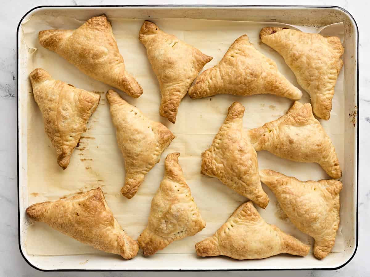 Freshly baked puff pastry samosas on a baking sheet.