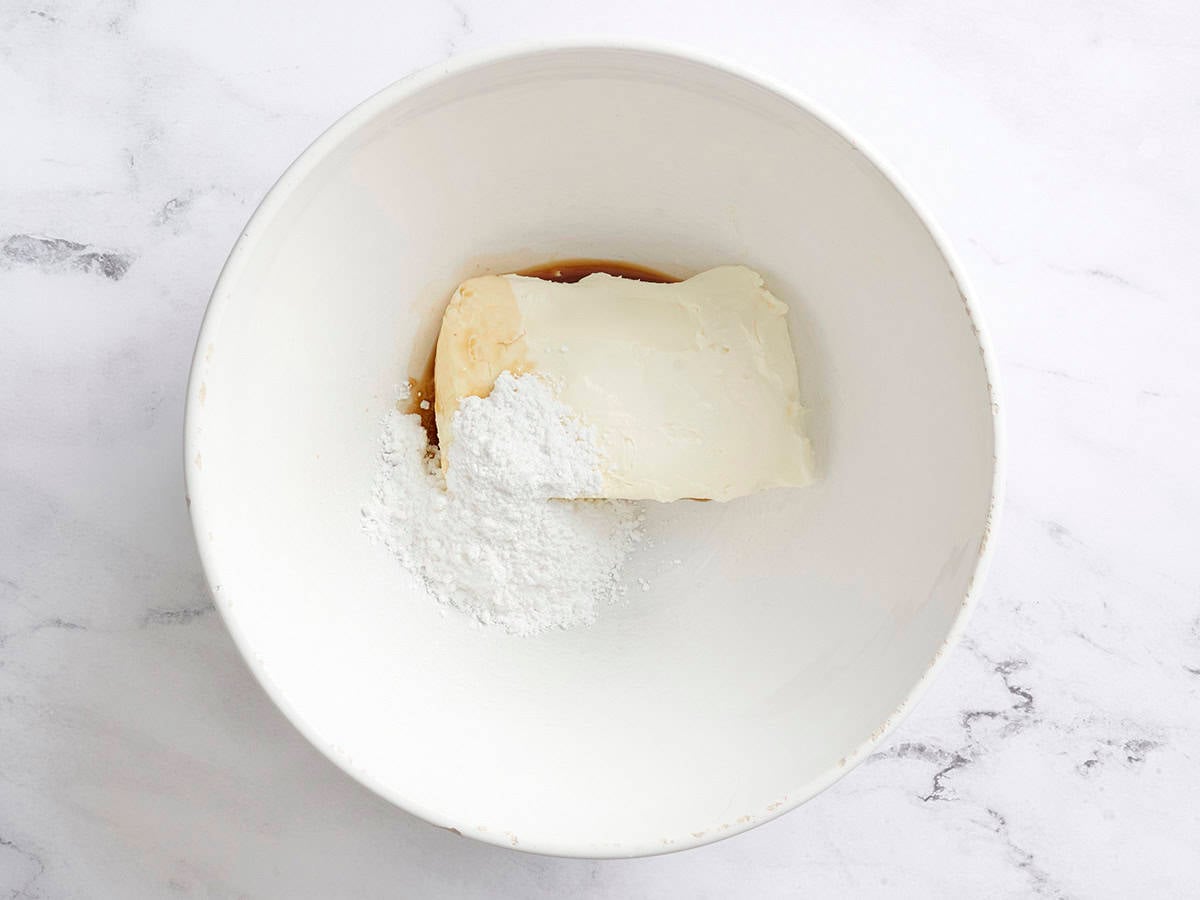 Vanilla extract, cream cheese, and powdered sugar in a bowl.