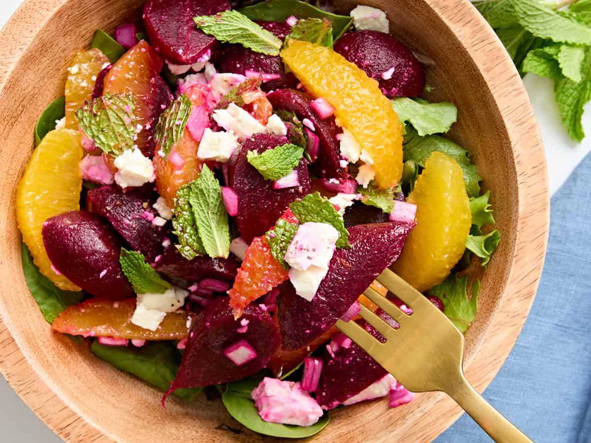 A fork taking some beet salad from a bowl.