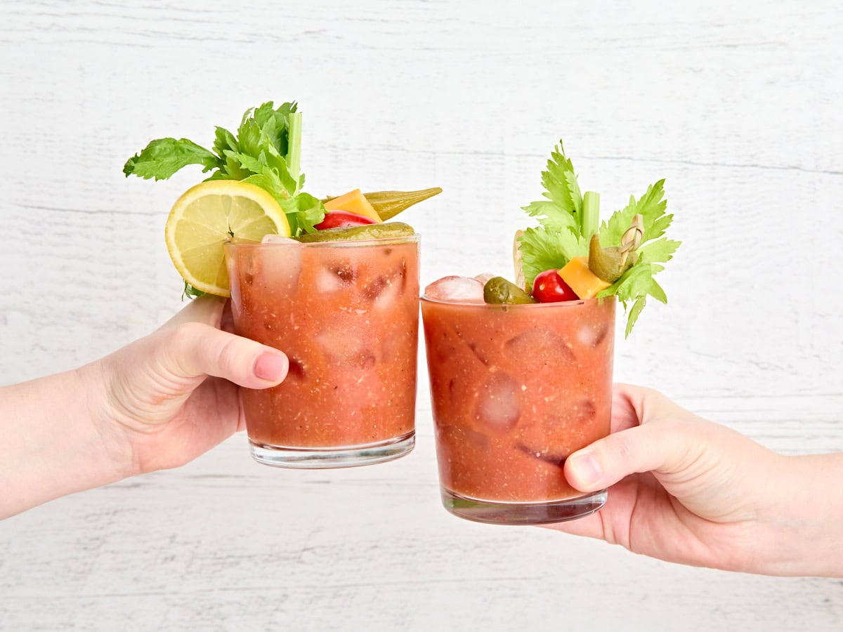 Two hands clinking together a glass of bloody mary each.