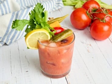 Side view of a homemade bloody mary in a glass with garnishes.
