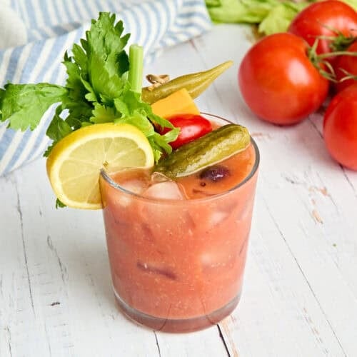 Side view of a homemade bloody mary in a glass with garnishes.