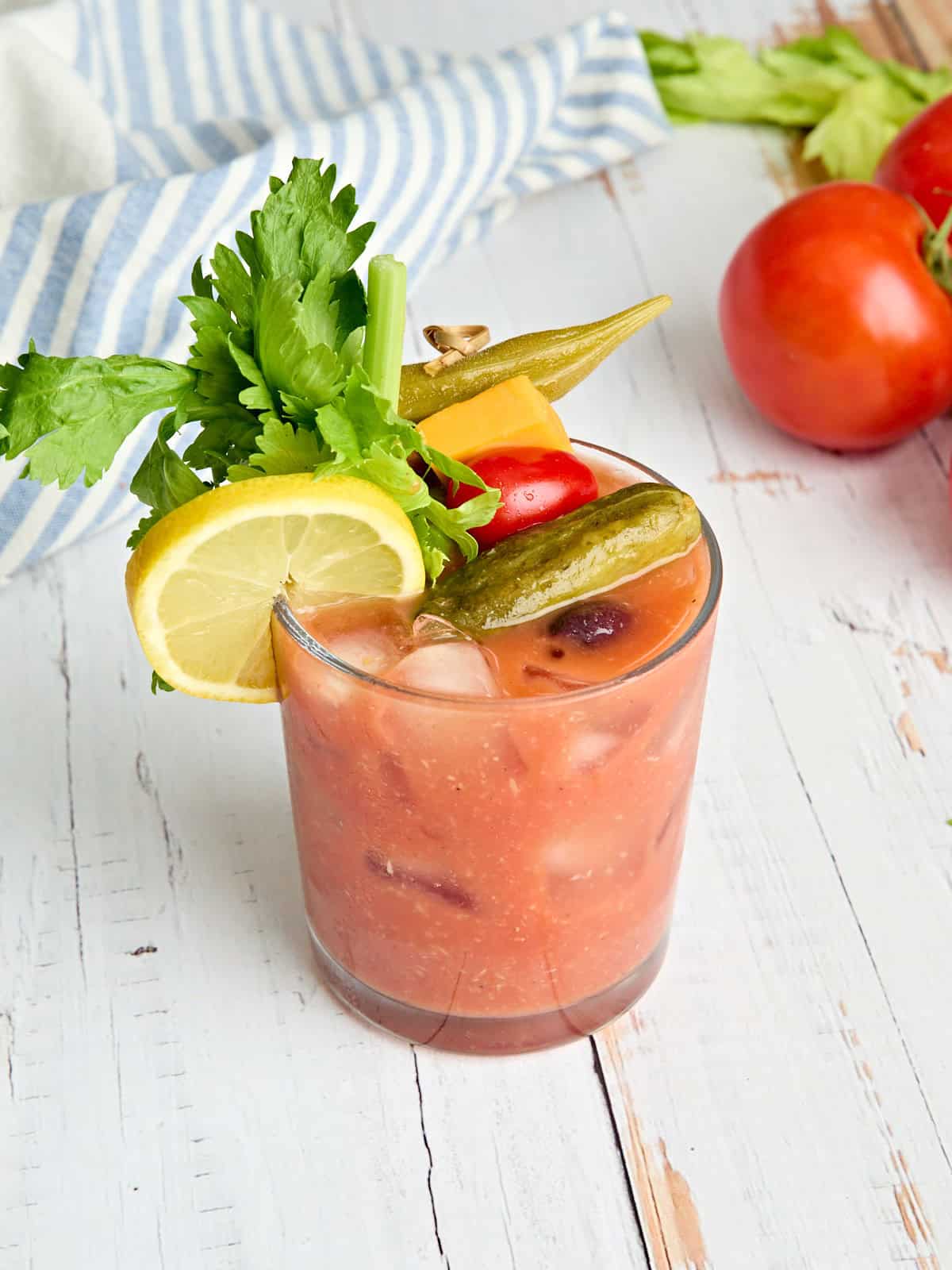 Side view of a homemade bloody mary in a glass with garnishes.