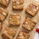 Overhead view of sliced cherry blondies on a piece of parchment paper.