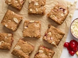 Overhead view of sliced cherry blondies on a piece of parchment paper.