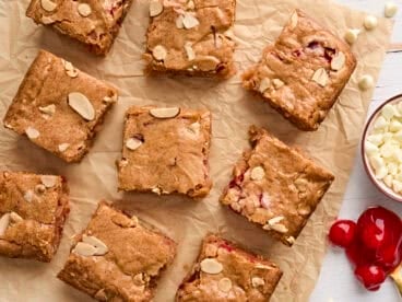 Overhead view of sliced cherry blondies on a piece of parchment paper.