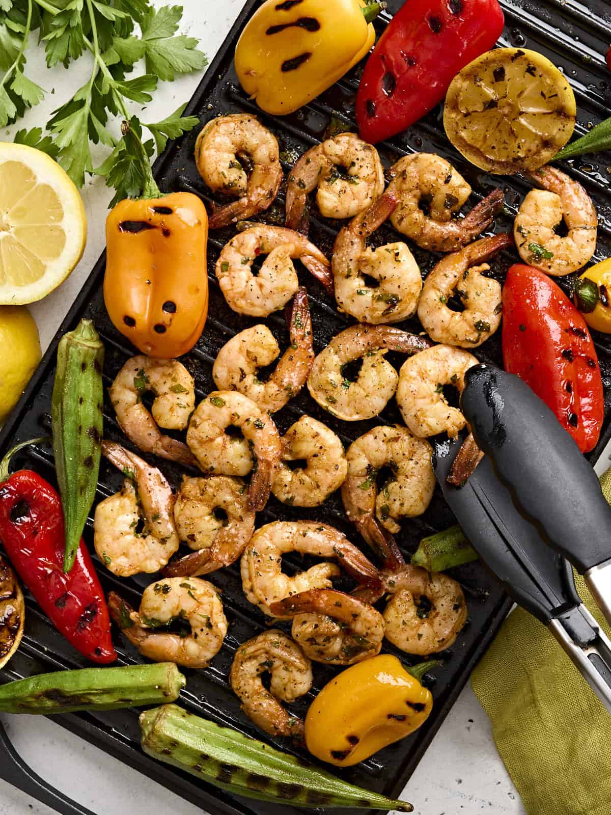 Overhead view of grilled shrimp on a grill with grilled vegetables.