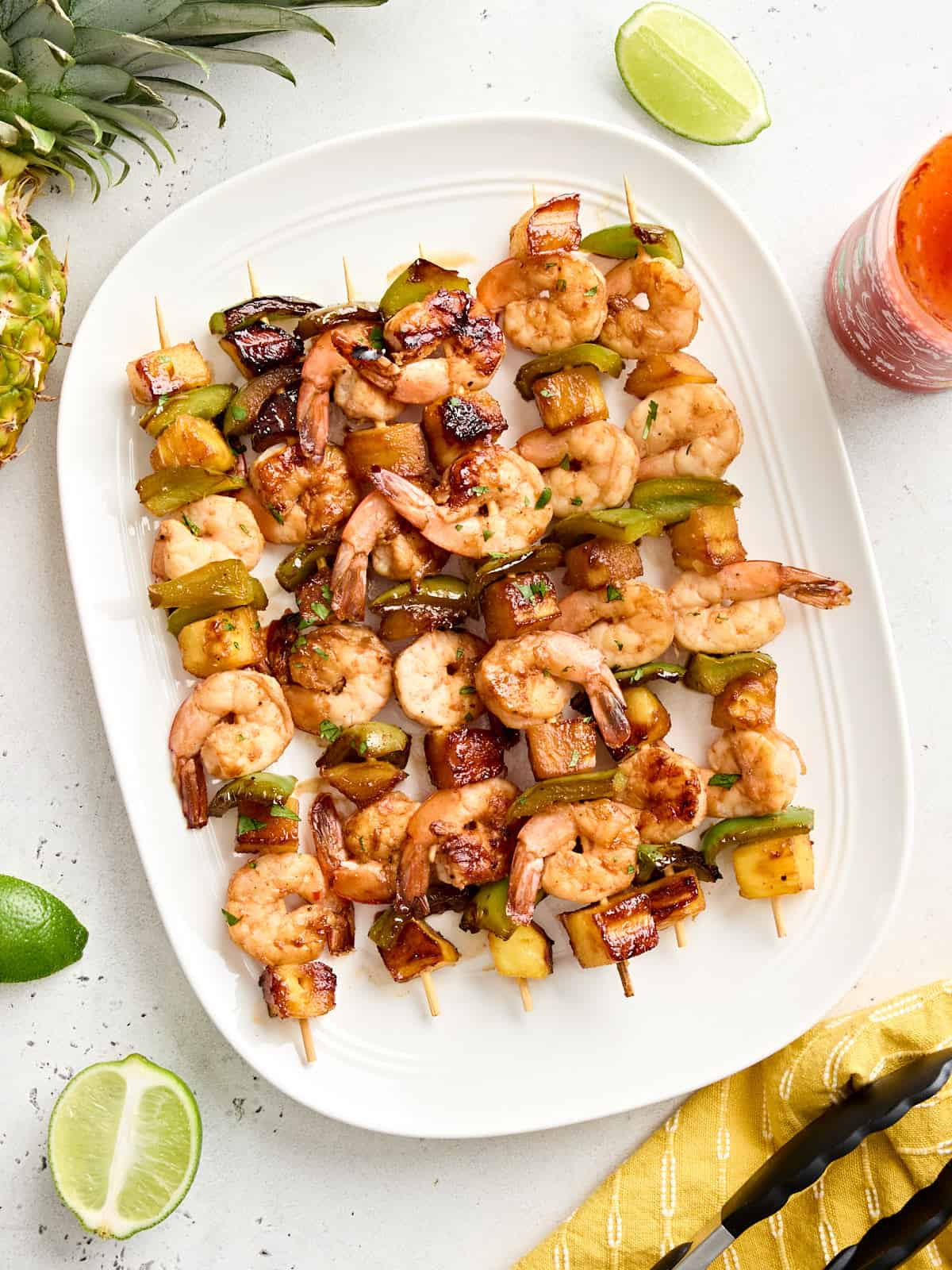 Overhead view of a platter of grilled shrimp and pineapple skewers.
