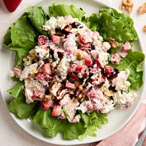 Overhead view of a strawberry chicken salad on a bed of greens.