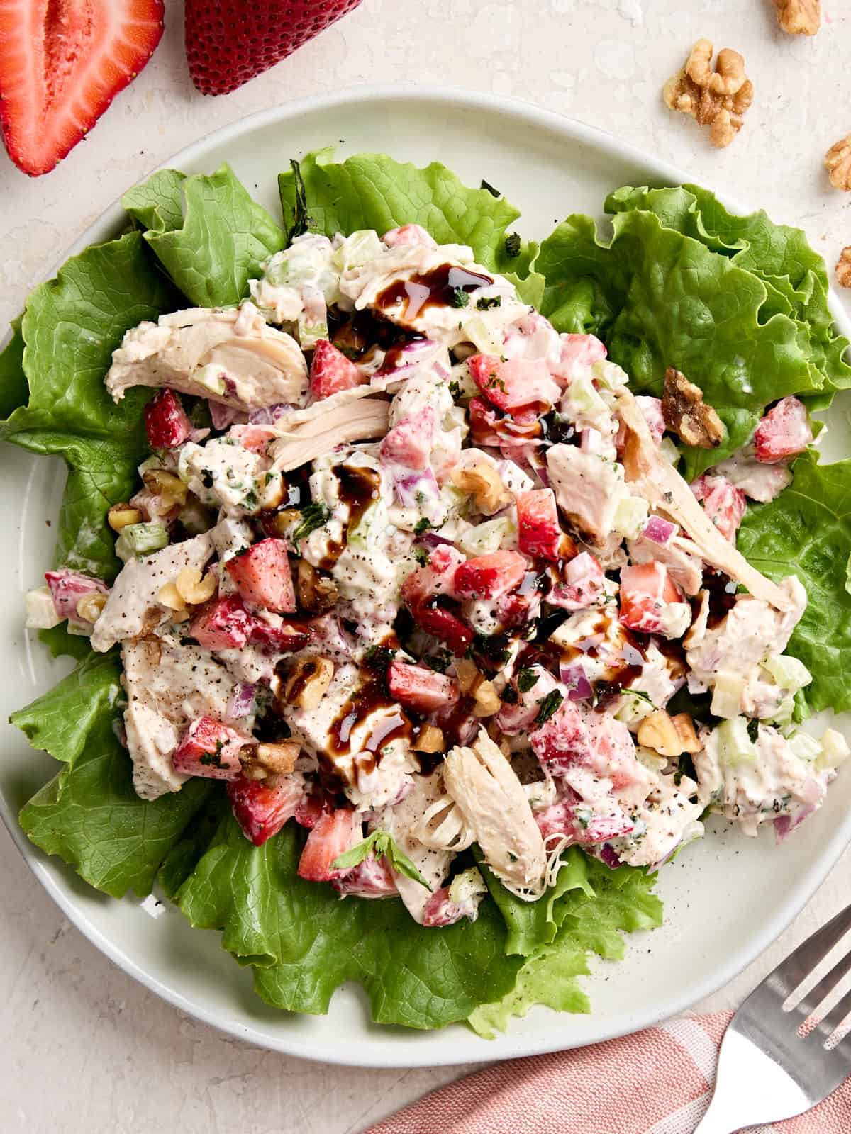Overhead view of a strawberry chicken salad on a bed of greens.