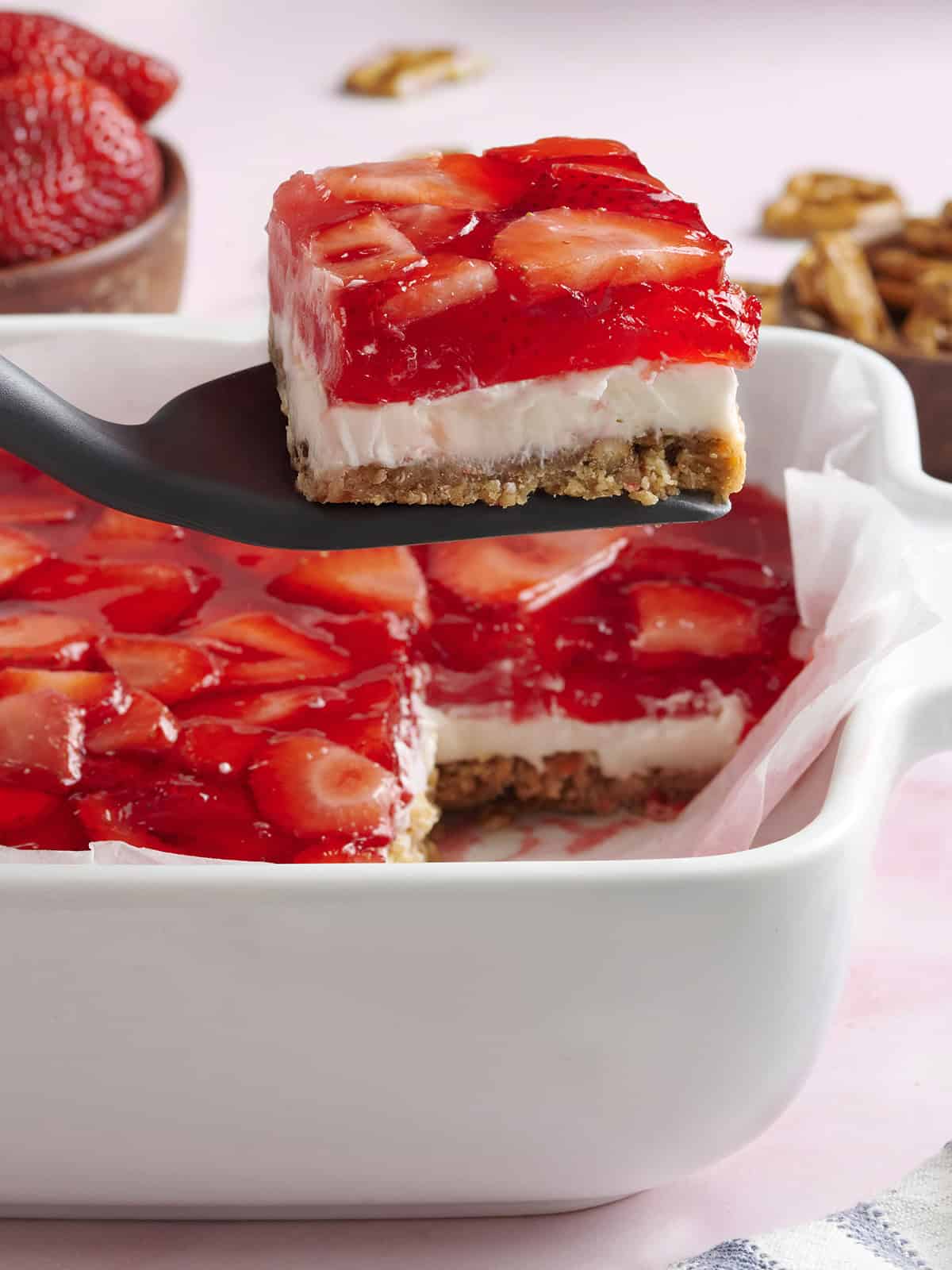 Strawberry pretzel salad in a baking dish with a slice being taken.