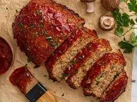 Overhead view of a homemade turkey mushroom meatloaf, with half of it cut into slices.