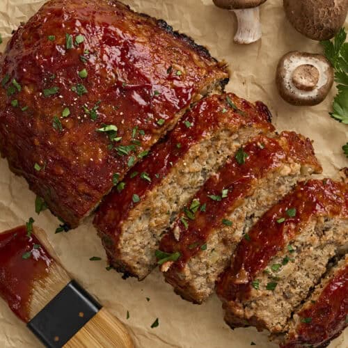 Overhead view of a homemade turkey mushroom meatloaf, with half of it cut into slices.